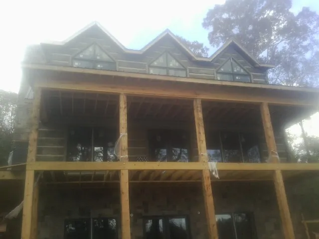 Dormers and porch framing on a large log home under construction — Roof Coating work by our crew in Park City